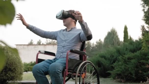 Ένα ανάπηρο άνθρωπο σε μια αναπηρική καρέκλα καρέκλα χρησιμοποιεί ένα κράνος εικονικής πραγματικότητας — Αρχείο Βίντεο
