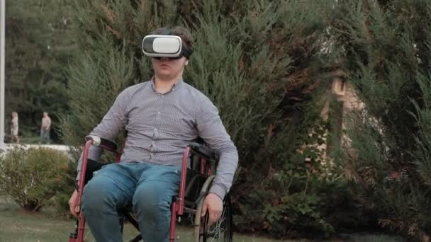 Ένα ανάπηρο άνθρωπο σε μια αναπηρική καρέκλα καρέκλα χρησιμοποιεί ένα κράνος εικονικής πραγματικότητας — Αρχείο Βίντεο