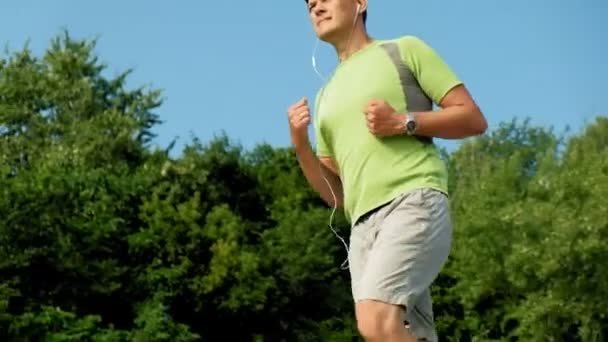 Zralý muž fitness se zabývá bek pod širým nebem, ve sluchátkách. Super pomalý pohyb — Stock video