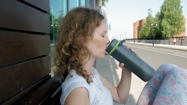 Спортивна жінка п'є пляшку води в парку в повільному русі — стокове відео