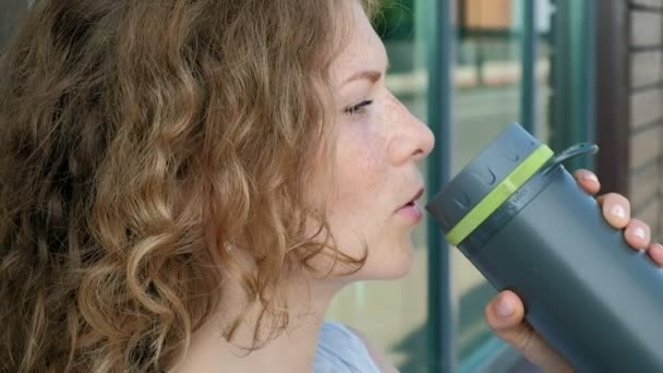 Deportiva bebiendo una botella de agua en un parque en cámara lenta — Vídeo de stock