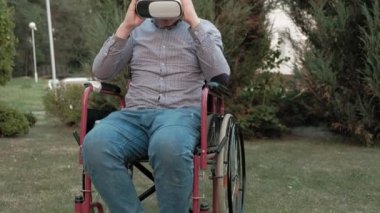 Bir tekerlekli sandalye Engelli bir erkekte sanal gerçeklik kask kaldırır