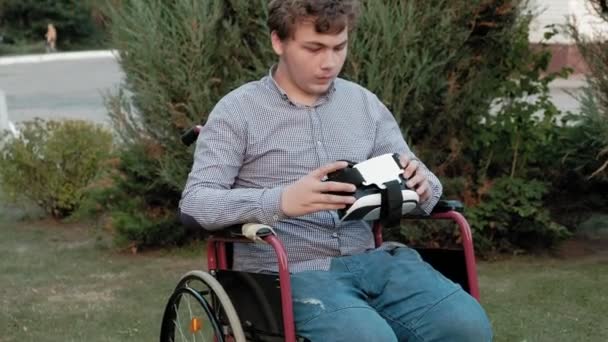 Een gehandicapte man in een rolstoel stoel jurken een vr-helm — Stockvideo