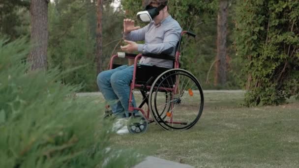 Postižený člověk v křesle invalidní vozík používá virtuální realita přilba — Stock video