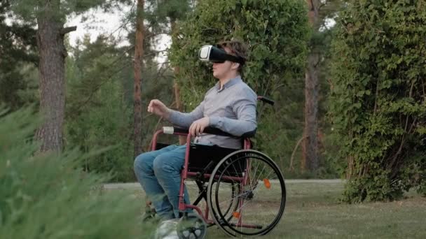 Um homem com deficiência em uma cadeira de rodas usa um capacete de realidade virtual — Vídeo de Stock