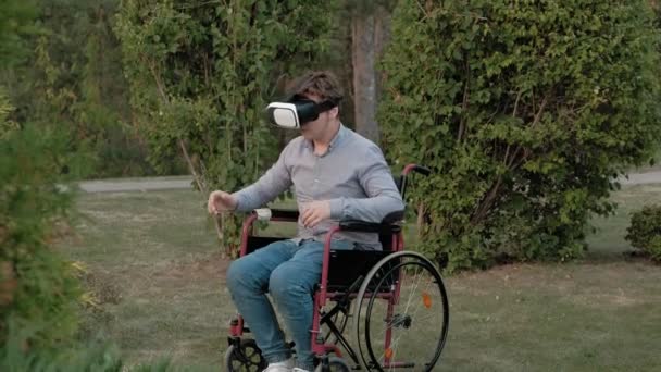 Seorang pria cacat di kursi roda menggunakan helm virtual reality — Stok Video