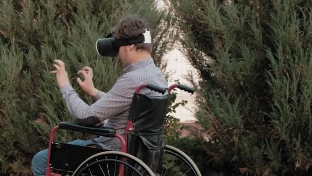 Un hombre discapacitado en silla de ruedas utiliza un casco de realidad virtual — Vídeo de stock