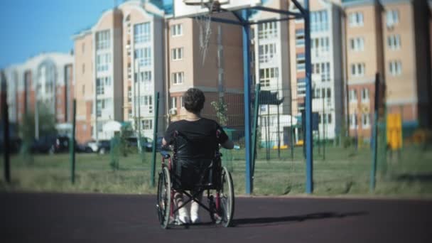 Gehandicapte man speelt basketbal van zijn rolstoel, op de open lucht — Stockvideo