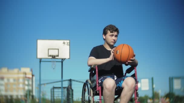 Людина з обмеженими можливостями грає в баскетбол зі свого інвалідного візка, на відкритому повітрі — стокове відео