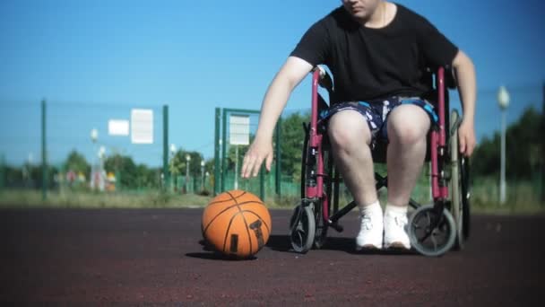 Gehandicapte man speelt basketbal van zijn rolstoel, op de open lucht — Stockvideo