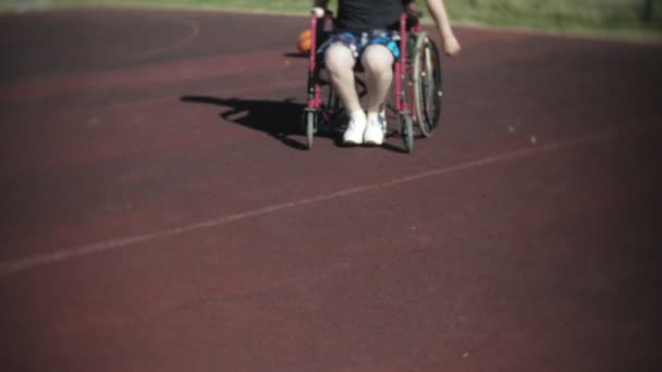 Инвалид играет в баскетбол со своего инвалидного кресла на открытом воздухе — стоковое видео