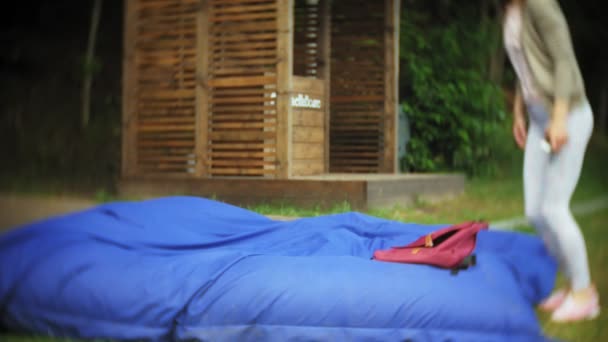 Jeune femme sautant couché dans un coin salon du parc sur des bouffées molles — Video