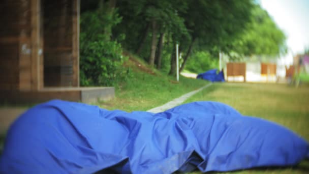 Молодая женщина прыгает лежа в гостиной парка на мягких слоеных подушках — стоковое видео