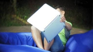 yumuşak puffs üzerinde Park lounge alanında yalan bir dizüstü bilgisayar, Olgun adam kullanır