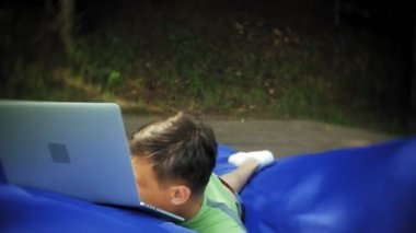 yumuşak puffs üzerinde Park lounge alanında yalan bir dizüstü bilgisayar, Olgun adam kullanır