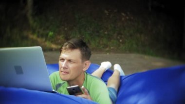 yumuşak puffs üzerinde Park lounge alanında yalan bir dizüstü bilgisayar, Olgun adam kullanır