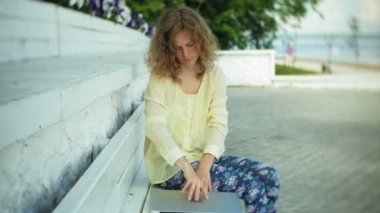 Park ahşap bir bankta bir dizüstü bilgisayar üzerinde çalışan güzel kadın