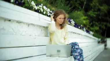 Park ahşap bir bankta bir dizüstü bilgisayar üzerinde çalışan güzel kadın