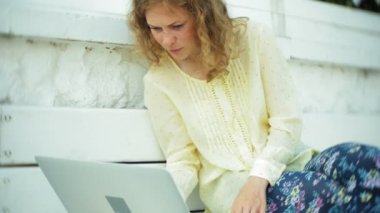 Park ahşap bir bankta bir dizüstü bilgisayar üzerinde çalışan güzel kadın