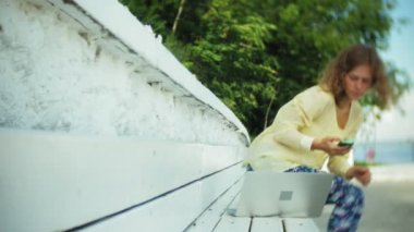 Park ahşap bir bankta bir dizüstü bilgisayar üzerinde çalışan güzel kadın