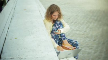 Park ahşap bir bankta bir dizüstü bilgisayar üzerinde çalışan güzel kadın