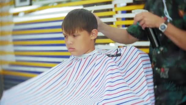 Pequena criança recebendo um corte de cabelo na barbearia . — Vídeo de Stock