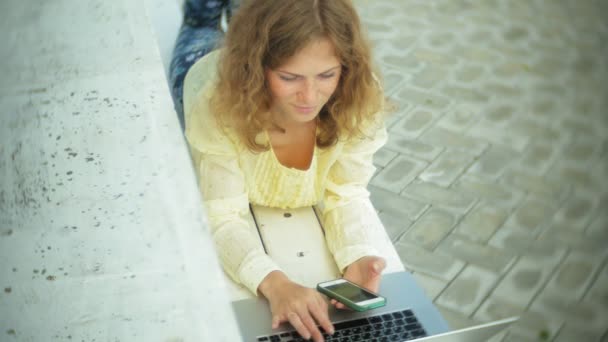 Bella donna che lavora su un computer portatile su una panchina di legno nel parco — Video Stock