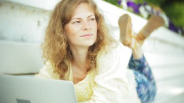 Park ahşap bir bankta bir dizüstü bilgisayar üzerinde çalışan güzel kadın