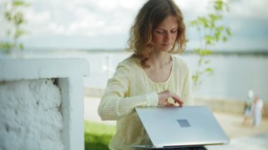 Park ahşap bir bankta bir dizüstü bilgisayar üzerinde çalışan güzel kadın