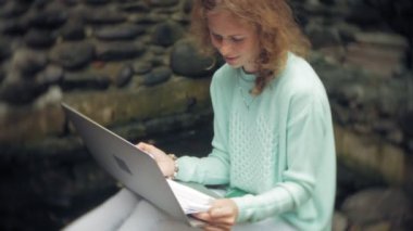 Kadın bir dizüstü bilgisayar ve taşlı duvar arka plan üzerindeki belgeler.