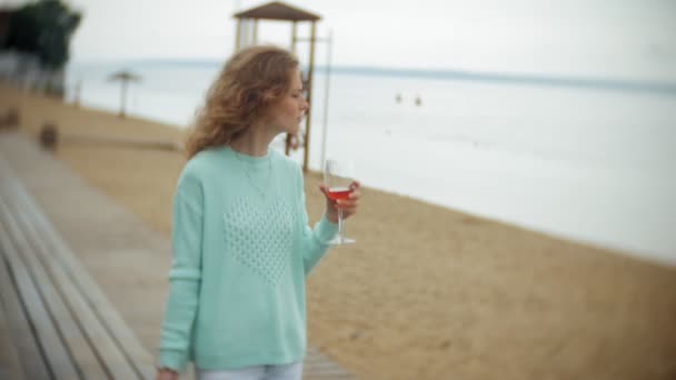 Een vrouw is met behulp van een smartphone tegen een achterwand. Dranken en wijn drinkt uit een glas — Stockvideo