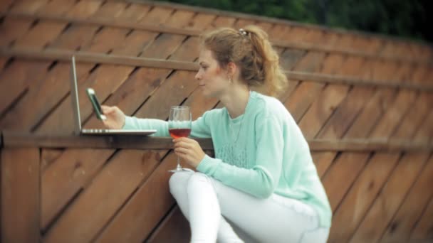 Uma mulher com um portátil e documentos. Bebidas e bebidas vinho de um copo — Vídeo de Stock