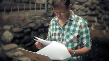 Dizüstü bilgisayar ve belgeleri bir stonewall arka plan üzerinde bir adam duvar işleri ve içecekler şarap cam