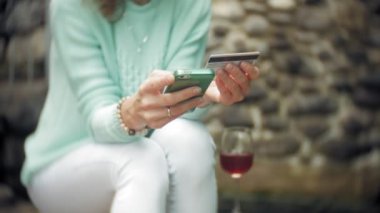 Bir kadın bir akıllı telefon arka duvarına karşı kullanıyor. İçki ve İçecek şarap cam