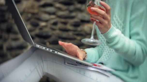 Femme avec un ordinateur portable et des documents sur le fond d'un mur pierreux. Boissons et boissons vin d'un verre — Video