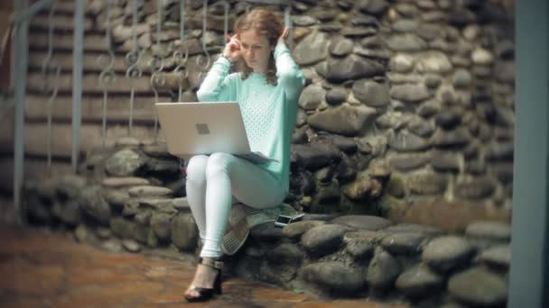 Mujer con portátil y documentos en el fondo de una pared de piedra — Vídeos de Stock