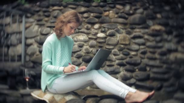 Donna con computer portatile e documenti sullo sfondo di una parete in pietra — Video Stock