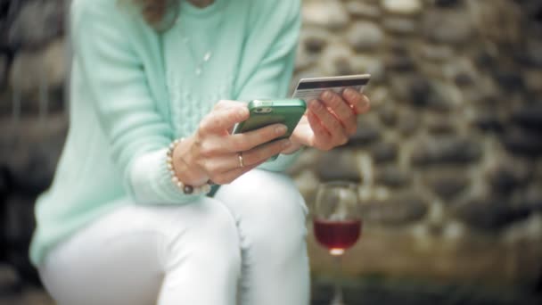 Egy nő használ egy okostelefon, a hátsó falnak. Italok és egy pohár bor ital — Stock videók