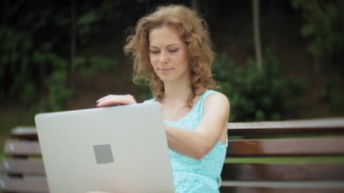 Sahilde bir dizüstü 4 k kullanan bir bankta oturan bir kadın