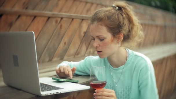 Uma mulher com um portátil e documentos. Bebidas e bebidas vinho de um copo — Vídeo de Stock