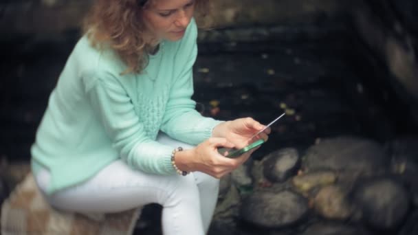Eine Frau fährt mit ihrem Smartphone gegen eine Rückwand. Getränke und Wein aus einem Glas — Stockvideo