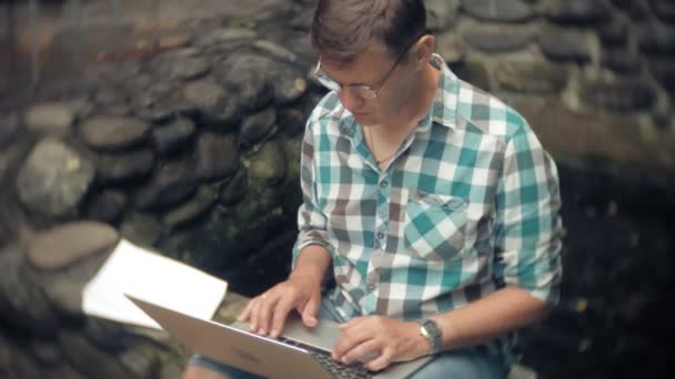 Homem Com Laptop Documentos Fundo Uma Parede Pedra Funciona Bebe — Vídeo de Stock