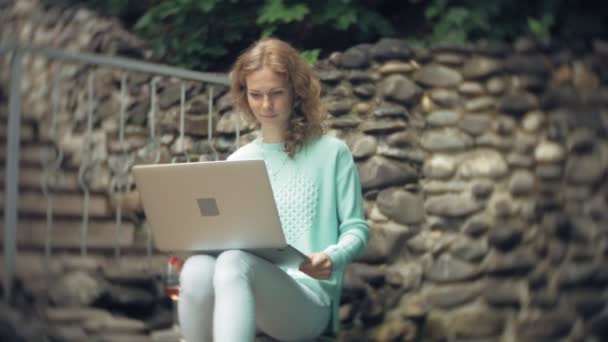 Femme avec un ordinateur portable et des documents sur le fond d'un mur pierreux . — Video