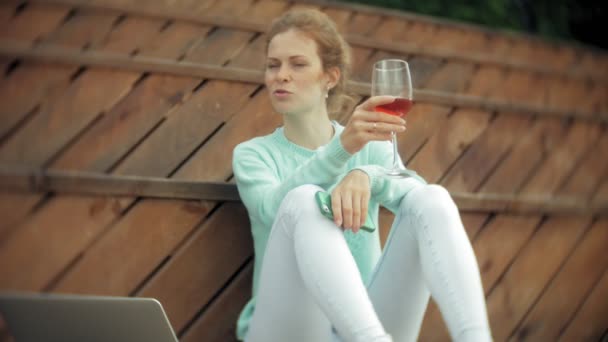 Woman with a laptop and documents. Drinks and drinks wine from a glass — Stock Video