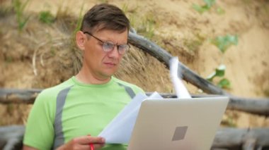 bir telefon bir güneşli gün ve içme şarap cam sahilde denizin kenarında oturan bir çağrı için malzeme çekme iş kağıtları ile bir dizüstü bilgisayarda çalışma meşgul olgun adam