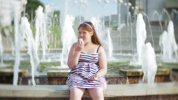 孩子, 小女孩吃冰淇淋在炎热, 炎热的夏日, 孩子们附近的喷泉 — 图库视频影像