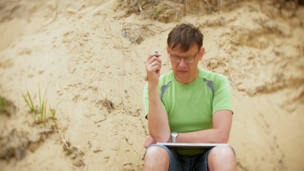 Ώριμος άνδρας σε μια αμμώδη παραλία καπνίζει vape — Αρχείο Βίντεο