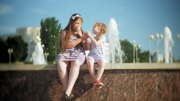 Barn, lilla flicka äter glass på en varm, förbränd sommardag, barn nära fontänen — Stockvideo
