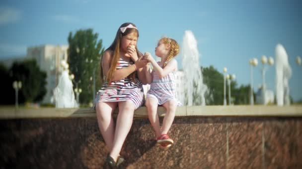 Enfant, Petite fille mangeant de la crème glacée un jour d'été chaud et torride, Enfants près de la fontaine — Video