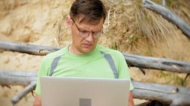 bir telefon bir güneşli gün ve içme şarap cam sahilde denizin kenarında oturan bir çağrı için malzeme çekme iş kağıtları ile bir dizüstü bilgisayarda çalışma meşgul olgun adam